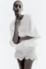 Remera blanca de corte holgado, cropped, con cuello redondo acanalado y hombros caídos.