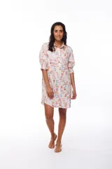 Vestido corto tipo camisero con estampado floral en tonos rosados, celestes y marrones. Tiene cuello camisero, mangas 3/4 abullonadas y cierre frontal con botones.