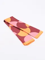 Pañuelo rectangular con estampado abstracto en tonos terracota, negro, blanco y beige.