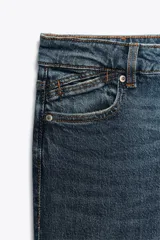 Pantalón de jean azul oscuro, de tiro bajo, corte slim fit y bootcut. Con cinco bolsillos y cierre frontal con cremallera y botón.