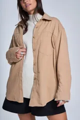 Sobrecamisa negra de gabardina con cuello camisero, cierre frontal con botones, mangas largas con puños abotonados y bolsillos de parche en el pecho.