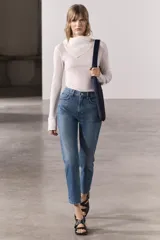 Jeans de tiro medio con corte recto, color azul denim con efecto lavado. Cuenta con cinco bolsillos, trabillas en la cintura y cierre frontal con cremallera y botón metálico.