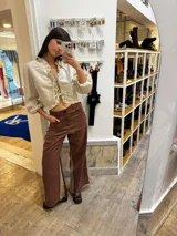 Pantalón sastrero color beige de lino, corte recto y tiro alto, con bordado de caballo en el bolsillo trasero.