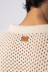 Camisa negra tejida de manga corta, con calado aireado, cuello tipo bowling y botones al tono. Diseño de corte relajado.