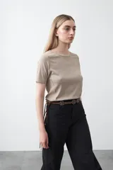 Remera de manga corta color beige claro, confeccionada en tejido acanalado elástico, con cuello redondo.