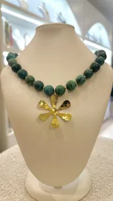 Collar de cuentas esféricas de piedra turquesa africana con dije de bronce en forma de flor.
