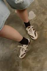 Zapatillas Adidas Samba con estampado animal print en blanco y negro, detalles en cuero beige y suela de goma color caramelo.