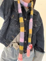 Bufanda angosta tejida a rayas horizontales en tonos rosa, lila, amarillo, verde y azul marino.