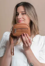 Monedero negro de simil cuero con correa para la mano, diseño práctico y compacto. Bolsillo principal con doble cierre, y un bolsillo frontal pequeño para llevar monedas.