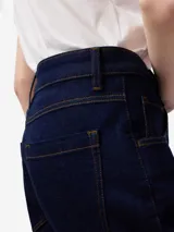 Pantalón tobillero de denim azul oscuro, con pespuntes a contraste, cierre con botón metálico, trabillas, cinco bolsillos y corte flare.