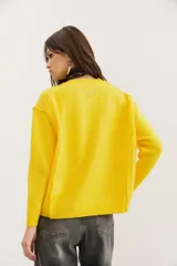 Sweater amarillo de punto con cuello redondo y mangas largas.
