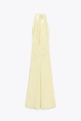 Vestido largo color amarillo pálido, con cuello halter que se ata en la nuca, escote en pico y frunces laterales.