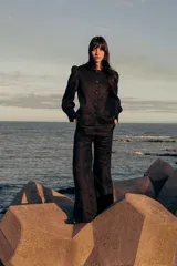 Pantalón negro de lino con corte flare, tiro medio y costuras verticales al frente.