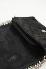 Cartera de mano negra con textura y correa de cadena plateada.