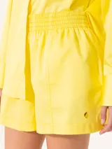 Short amarillo de tiro alto con pinzas delanteras y cierre invisible lateral.