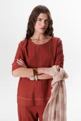 Blusa de lino color beige claro, con mangas 3/4 y cuello redondo. Presenta pespuntes a contratono en el centro, puños y ruedo.