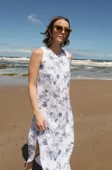 Vestido midi sin mangas con estampado floral azul sobre fondo blanco, tajos laterales y cierre con botón en la espalda.