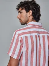Camisa de hombre de manga corta, confeccionada en lino con rayas verticales blancas y ladrillo. Tiene cuello abotonado y bolsillo en el pecho.