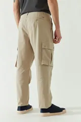 Pantalón cargo color beige para hombre, de corte recto, con bolsillos laterales y traseros. Se ajusta a la cintura con cinturón de cuero marrón.