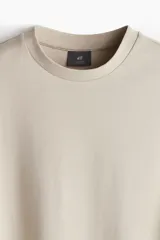 Remera color beige de corte holgado, cuello redondo y mangas cortas.