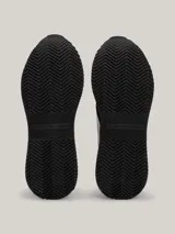 Zapatillas deportivas Tommy Hilfiger de piel negra con paneles con monogramas TH en relieve y detalles en blanco y dorado.