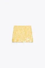 Minifalda dorada cubierta de lentejuelas, con forro interior y cierre lateral oculto.