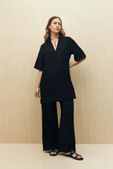 Vestido corto negro de línea relajada con cuello tipo solapa y escote en V profundo, mangas cortas amplias y calce suelto.