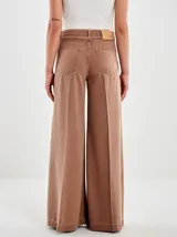 Pantalón de jean color marrón óxido, estilo ancho (wide leg) con tiro alto, pliegues frontales y posteriores, y diseño de cinco bolsillos.