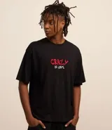 Remera negra de algodón con corte boxy, cuello redondo y mangas cortas. Estampado en la espalda de Lola Bunny besando a Bugs Bunny, con corazones y texto "Lola and Bugs Bunny".