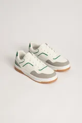 Zapatillas deportivas acordonadas blancas con detalles en verde y gris.