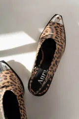 Zapato tipo slingback con estampado animal print, punta afilada con detalle metálico plateado y logo Aura en la plantilla.