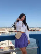 Bandolera pequeña de símil cuero color camel, con dos compartimentos principales con cierre. Incluye una correa ancha de tela estampada con motivos geométricos en tonos tierra y blanco.