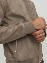 Campera bomber color marrón claro de cuero sintético, con cuello tipo baseball, cierre frontal con cremallera, bolsillos laterales con cremallera y bolsillo en la manga.