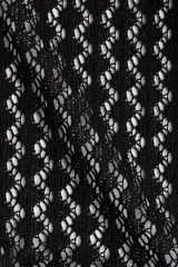 Top corto de punto calado negro con escote redondo, frente abierto con lazos y mangas cortas abullonadas con volados.