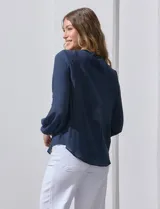 Blusa azul marino de manga larga con cuello redondo con detalle de broderie y cierre frontal con botones.