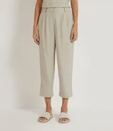 Pantalón zanahoria color beige de liocel, con pliegues delanteros, bolsillos laterales y cierre con cremallera y botón.