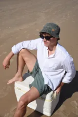 Short de baño verde con estampado de hojas y flores en tonos verde oscuro y marrón. Tiene bolsillos laterales y traseros, cintura elástica con cordón ajustable y corte clásico.