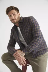 Sobrecamisa de viyela para hombre con estampado de cuadros en rojo y negro. Presenta cierre frontal con botones, bolsillos en el pecho con solapa y botón, y un interior capitoneado para mayor abrigo. Cuenta con un logo en grifa de cuero.