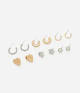 Kit de seis pares de caravanas y argollas de metal con baño mixto en tonos dorados y plateados. El conjunto incluye un par de caravanas con forma de corazón dorado, un par de estrellas plateadas, un par de esferas plateadas y tres pares de argollas de distintos tamaños y acabados, incluyendo un par con diseño trenzado.