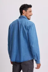 Camisa de jean celeste de manga larga con cuello clásico, cierre con botones a presión y dos bolsillos con solapa abotonada en el pecho.