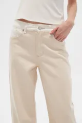 Pantalón jean color beige, de corte recto y holgado, con cintura alta y diseño color block en la parte superior.
