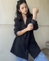 Blazer negro de corte oversize, con solapas de muesca, cierre cruzado con doble botonadura y bolsillos delanteros con solapa.