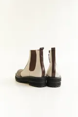 Botas cortas de cuero color marrón y beige, con elástico lateral y suela track color negro.