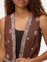Chaleco sin mangas color marrón con cuello tipo pañuelo y estampado repetido en tonos claros.
