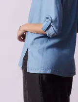 Blusa celeste en lyocell, con cuello a la base con solapa, escote en V y abertura central con botones. Manga larga regulable con presilla y botón.