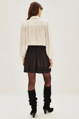 Minifalda negra plisada con dos volados en el ruedo y un cinturón decorativo con detalles metálicos y de perlas.