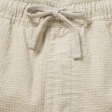 Bermuda color beige con textura tipo waffle, de corte recto y largo a la rodilla. Cuenta con cintura elástica y cordón ajustable.