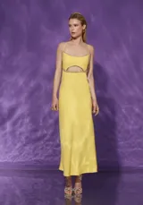 Vestido largo amarillo con breteles finos y abertura en la cintura con detalle de strass.