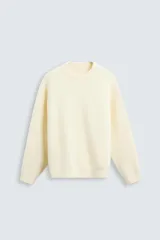 Jersey color crema de punto con textura, cuello redondo, manga larga y corte relaxed fit.