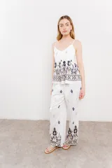 Pantalón blanco con estampado geométrico en azul y marrón, de calce relajado y caída fluida.